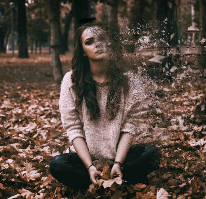 Sad woman sitting on leaves disintegrating