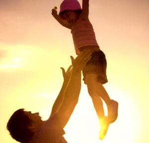 Parent tossing child in the air and catching her - Trauma-Informed Parentin