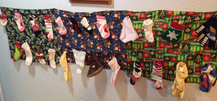 advent calendar made of socks, hats, gloves hanging on blanket on wall