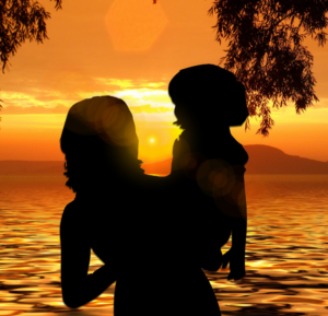 Mother holding child on beach in sunset