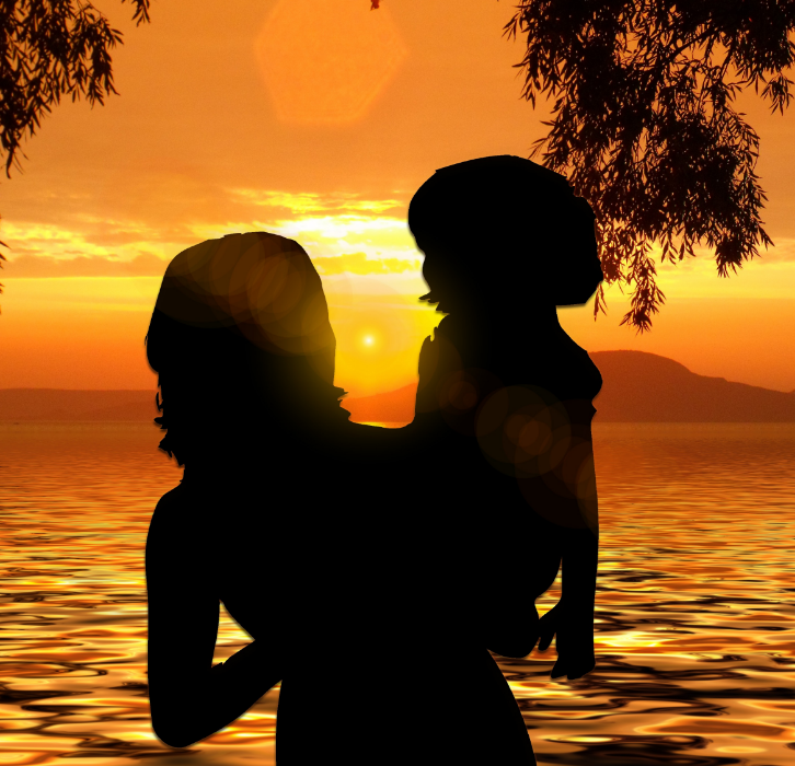 Mother holding child on beach in sunset