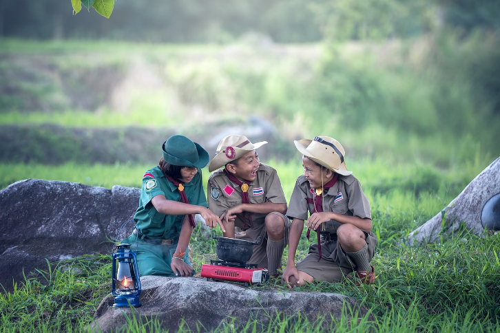 3 children in scout uniforms in the woods