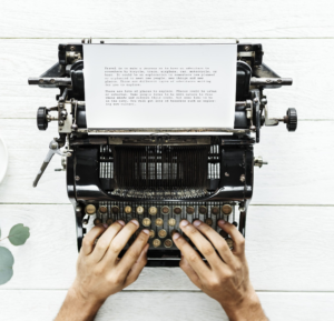 hands typing at manual typewriter with paper in it