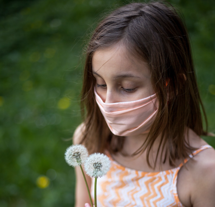 lonely girl wearing dress and mask holding dandelions